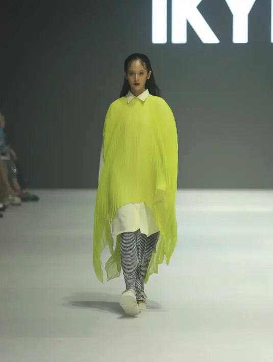 IKYK menampilan warna-warna cerah, seperti dress asimetris plisket warna hijau neon dengan gaya layering mengenakan inner kemeja panjang dan rok hitamnya.  [Fimela/Daniel Kampua]
