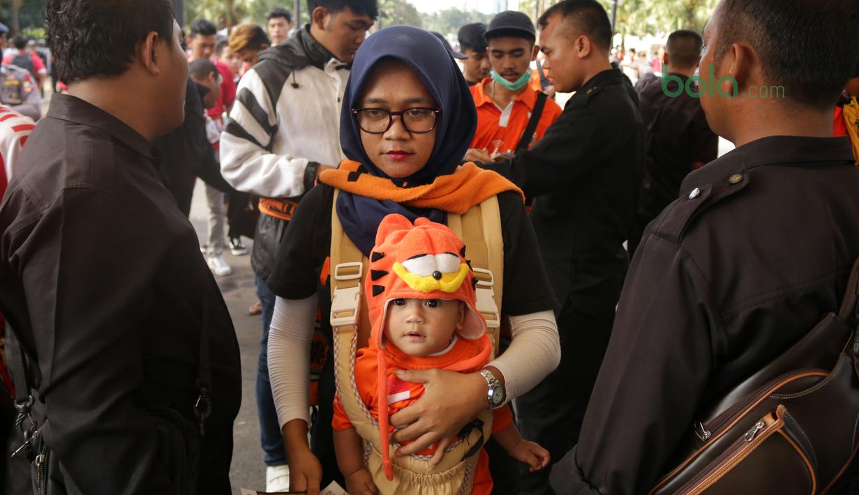 Orang tua dan bayi melewati pemeriksaan sebelum menonton laga Piala AFC 2018 antara Persija Jakarta vs Song Lam Nghe An di Stadion Utama GBK, Rabu (14/3/2018). Panpel menjual sekitar 65.000 lembar tiket. (Bola.com/Surya Bima Mahendarta)
