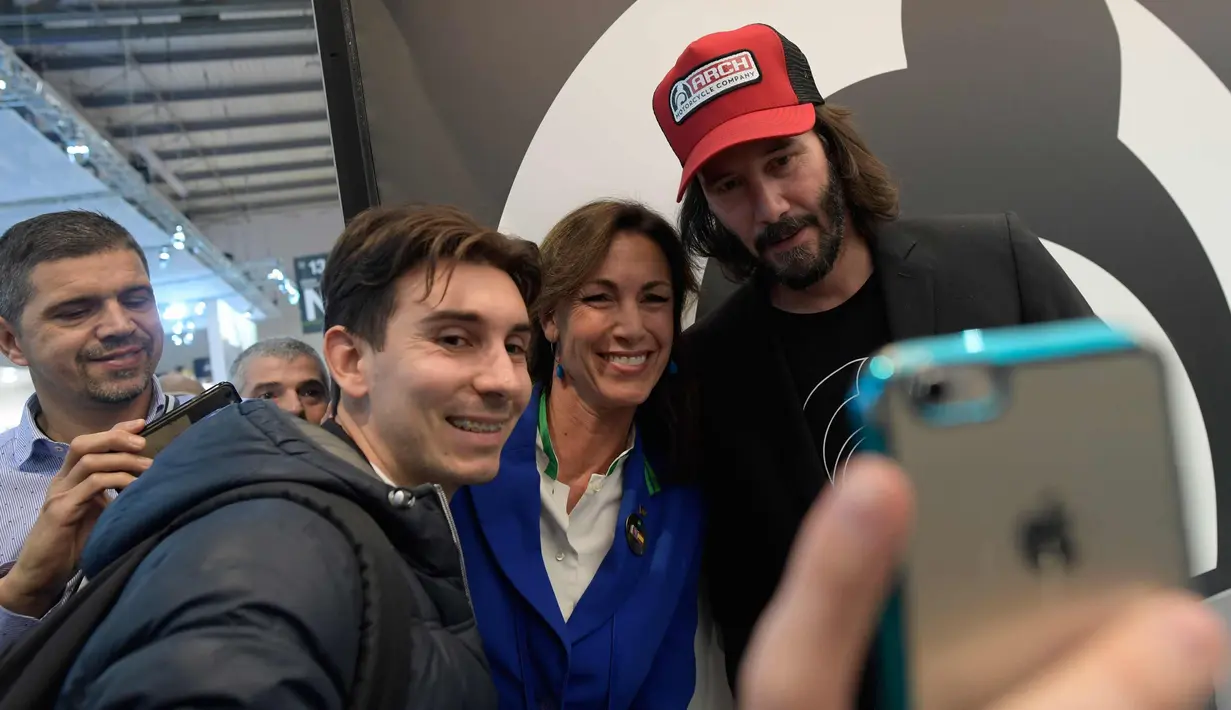 Aktor Keanu Reeves (kanan) berselfie dengan para pengunjung di Stand Motor Arch selama pameran Moto Milano 2017 (EICMA l'Esposizione Internationale del Ciclo e Motociclo) di Milan, Italia, (8/11). (AFP Photo/Miguel Medina)