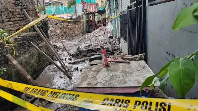 Garis polisi terpasang di sekeliling lokasi robohnya tembok pembatas sekolah di Palmerah, Jakarta Barat, Jumat (21/11/2025).