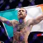 Conor McGregor mengibarkan bendera Irlandia setelah mengalahkan Donald 'Cowboy' Cerrone pada pertarungan kelas welter UFC 246 di T-Mobile Arena, Las Vegas, Amerika Sertikat, Sabtu (18/1/2020). McGregor mengalahkan Cowboy pada detik ke-40. (AP Photo/John Locher)