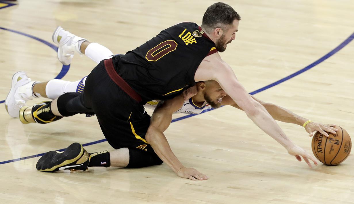 Pemain Warriors, Stephen Curry (bawah) berebut bola dengan pemain Cavaliers, Kevin Love pada gim pertama final NBA basketball di Oakland, California, (31/5/2018). Warriors menang 124-114. (AP/Marcio Jose Sanchez)