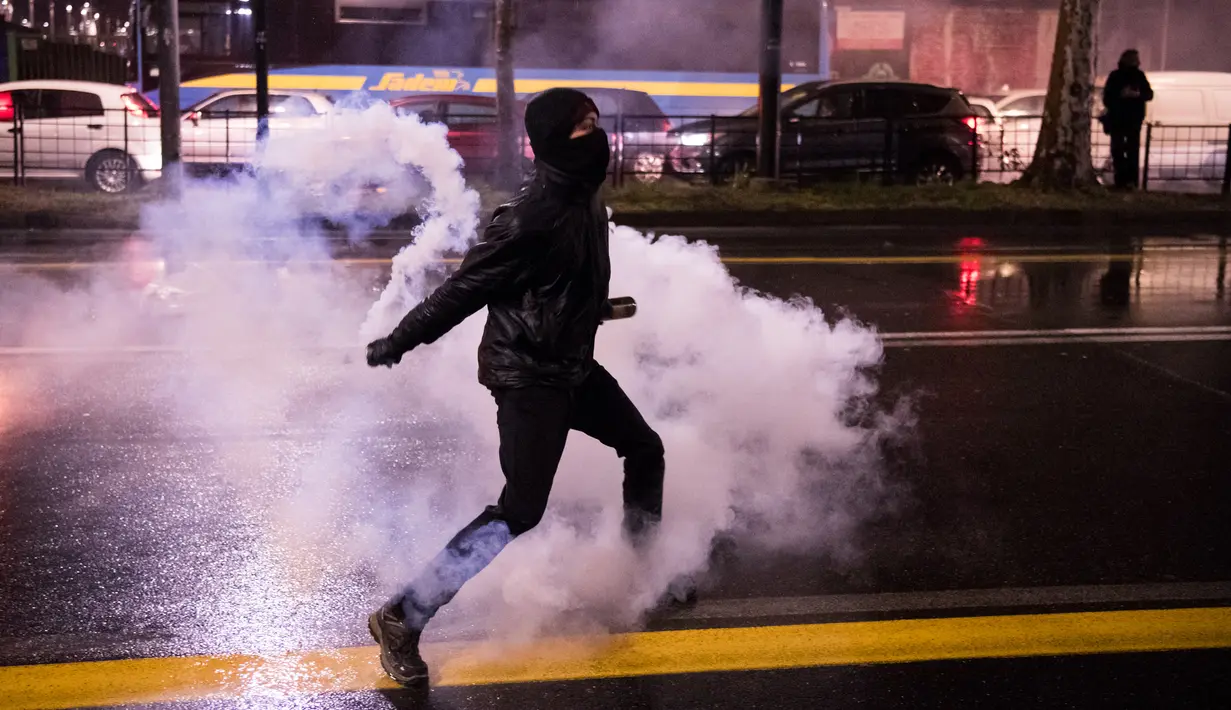 Seorang aktivis antifasis melempar tabung gas air mata ke petugas keamanan setempat saat terjadi huru-hara dalam demonstrasi di Turin, Italia (22/2). (AFP Photo/Piero Cruciatti)