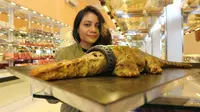 Natalia, salah satu pembeli sedang berposes bersama roti buaya berkalung ban di toko roti di Jalan RE Martadinata, Palu. (Liputan6.com/ Heri Susanto)