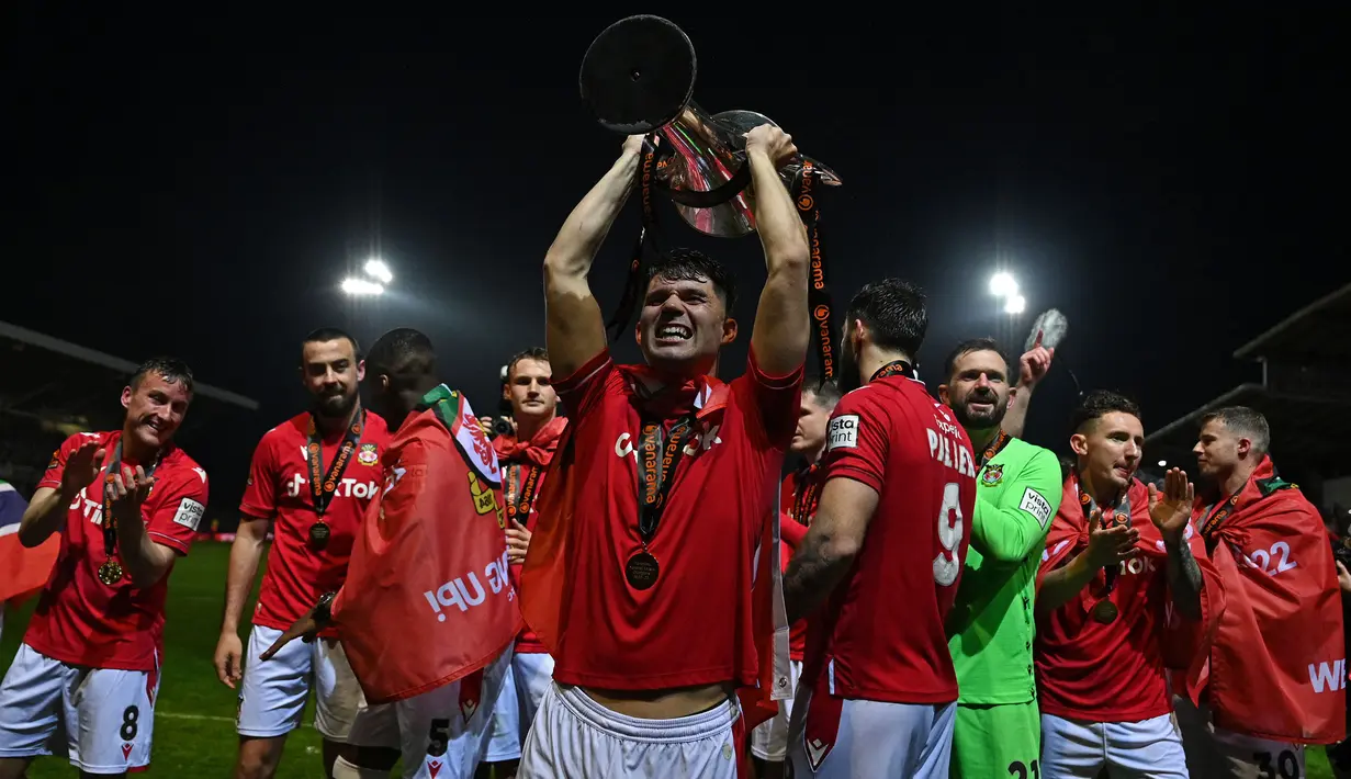 Sejumlah pemain Wrexham merayakan kemenangan timnya saat laga English National League antara Wrexham melawan Boreham Wood di Racecourse Ground Stadium, Wrexham, Wales, Sabtu (22/04/2023). Wrexham menang dengan skor 3-1 dan berhasil promosi ke Liga Dua Inggris. (AFP/Oli Scarff)