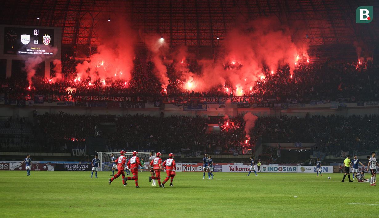 Suporter Persib Bandung menyalakan suar usai timnya mencetak gol penyeimbang 1-1 saat babak penyisihan Grup C Piala Presiden 2022 antara Persib Bandung melawan Bali United di Stadion Gelora Bandung Lautan Api, Bandung, Minggu (12/06/2022). (Bola.com/Bagaskara Lazuardi)