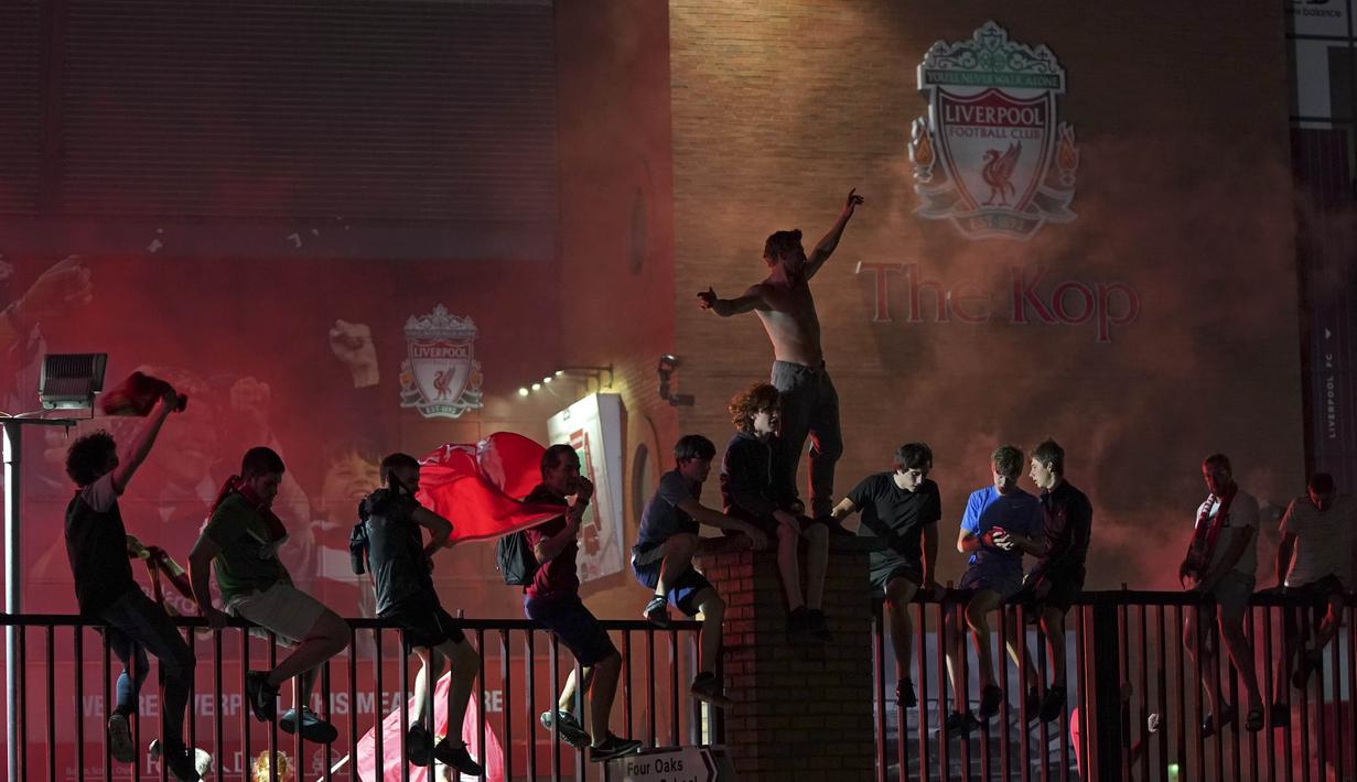 Suporter Liverpool merayakan gelar juara Premier League di depan Stadion Anfield, Kamis (25/6/2020). Titel juara Liga Inggris 2019-20 ini merupakan gelar pertama Liverpool setelah puasa selama 30 tahun. (AP/Jon Super)