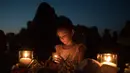 Lucretia Martinez (7) menyalakan lilin untuk mengenang korban penembakan di sekolah Santa Fe, Texas, Amerika serikat, Jumat (18/5). Sebanyak 10 orang tewas dalam tragedi penembakan tersebut. (AFP)
