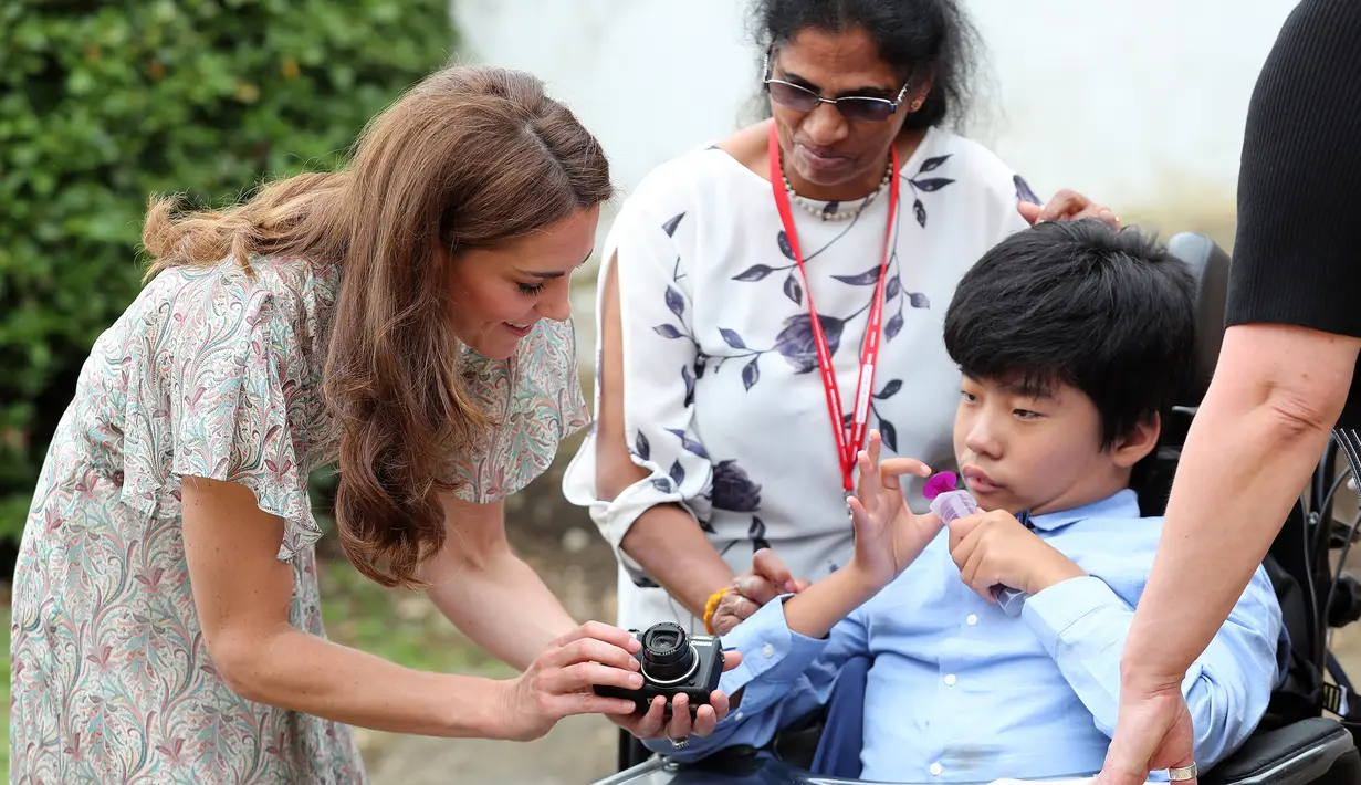 Duchess of Cambridge Kate Middleton berbincang dengan seorang anak saat ikut serta belajar fotografi dengan Action for Children di Kingston upon Thames, Inggris (25/6/2019). (AFP Photo/Chris Jackson)