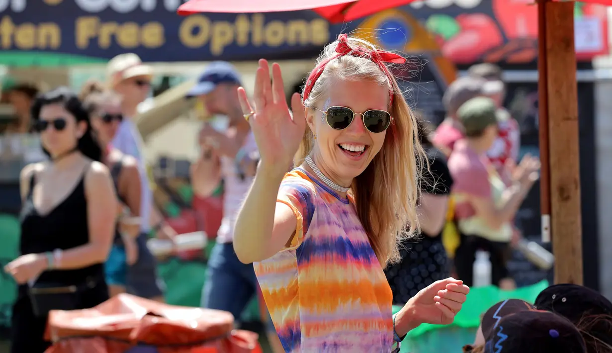 Seorang wanita tersenyum saat hari kedua Festival Glastonbury di Worthy Farm, Somerset, Inggris (28/6/2019). Gelombang panas yang melanada bagian-bagian Eropa tidak menyurutkan pengunjung untuk berkumpul di festival ini. (AP Photo/Joel C Ryan)