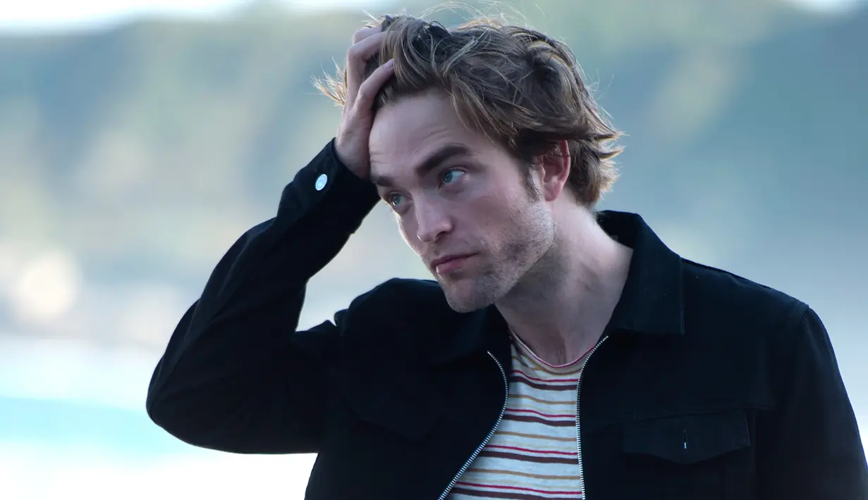 Aktor Inggris Robert Pattinson merapihkan rambutnya saat sesi pemotretan untuk mempromosikan filmn terbarunya "High Life" selama Festival Film San Sebastian ke-66, di kota Basque, San Sebastian, Spanyol utara (27/9). (AFP Photo/Ander Gillenea)