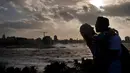 Suami istri berpelukan saaat ombak besar terlihat di laut Malecon di Havana, Kuba (21/12). Letak kota yang berdiri pada tahun 1515 ini relatif strategis. (AP Photo / Ramon Espinosa)