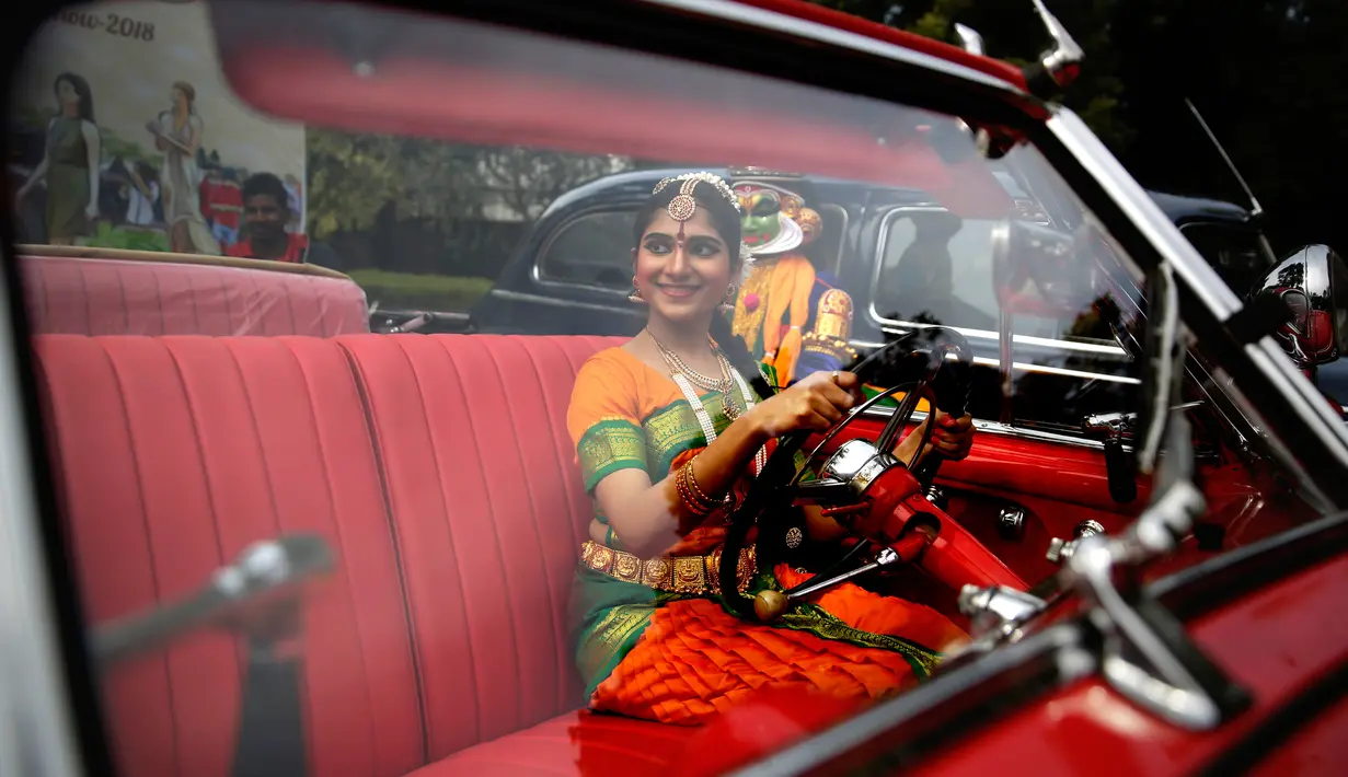 Penari berpose dengan mobil vintage yang baru direstorasi dalam pameran 21 Gun Salute Heritage and Cultural Trust di New Delhi, India, Selasa (6/2). (AP Photo/Altaf Qadri)