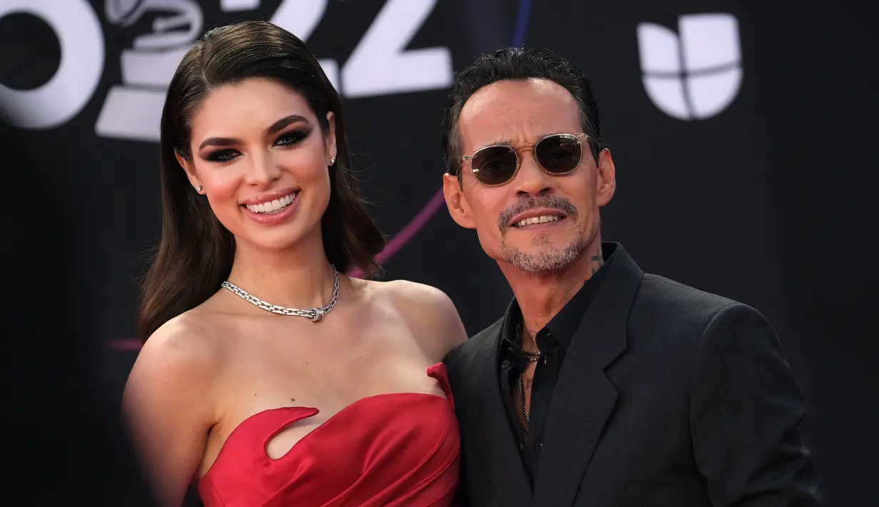 Marc Anthony bersama tunangannya model Paraguay Nadia Ferreira berpose saat tiba menghadiri penghargaan Grammy Latin ke-23 di Michelob Ultra Arena Mandalay Bay di Las Vegas, Nevada, pada 17 November 2022. Pelantun Vivir Mi Vida menyisir rambutnya ke belakang dan mengenakan sepasang warna aviator berbingkai bening untuk melengkapi tampilan karpet merahnya. (AFP/Chris Delmas)