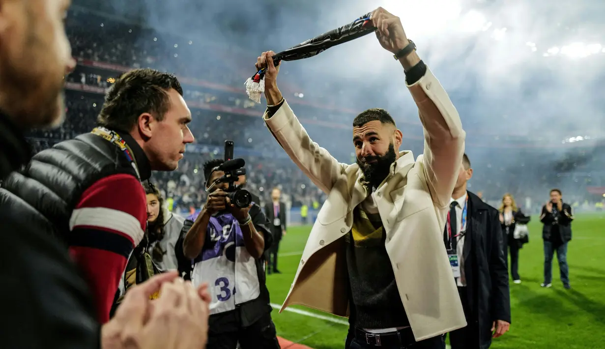 Pemain Real Madrid Karim Benzema (tengah) memberi isyarat kepada para penggemar saat penyerahan trofi Ballon d'Or miliknya pada babak pertama pertandingan sepak bola L1 Prancis antara Olympique Lyonnais (OL) dan OGC Nice di Stadion Groupama, Decines-Charpieu, Prancis, 11 November 2022. Momen itu juga menandai peringatan 35 tahun Bad Gones, fans utama pendukung Lyon. (OLIVIER CHASSIGNOLE/AFP)
