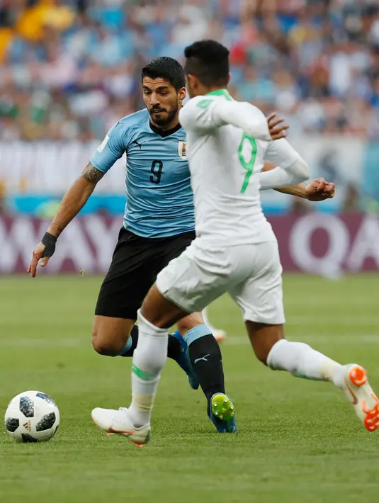 Penyerang Uruguay, Luis Suarez berebut bola dengan pemain Arab Saudi Hatan Bahbir pada pertandingan kedua Grup A Piala Dunia 2018 di Rostov Arena, Rabu (20/6). Uruguay mengalahkan Arab Saudi 1-0 berkat gol Suarez di babak pertama. (AP/ Darko Vojinovic)