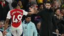 Pemain Arsenal, Myles Lewis-Skelly melakukan tos dengan pelatih Mikel Arteta saat digantikan dalam laga lanjutan Liga Inggris 2024/2025 melawan Manchester City di Emirates Stadium, London, Minggu (03/02/2025). (AFP/Glyn Kirk)