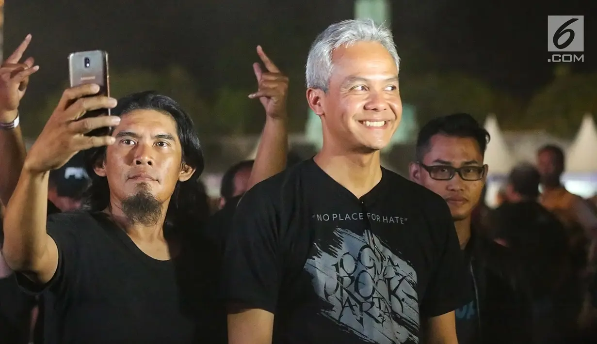 Gubernur Jawa Tengah, Ganjar Pranowo tiba untuk menonton Jogjarockarta 2018 di Stadion Kridosono Yogyakarta (27/10). Kehadiran Ganjar menarik perhatian penonton yang langsung mengerubutinya untuk bersalaman maupun berfoto. (Fimela.com/Bambang E.Ros)