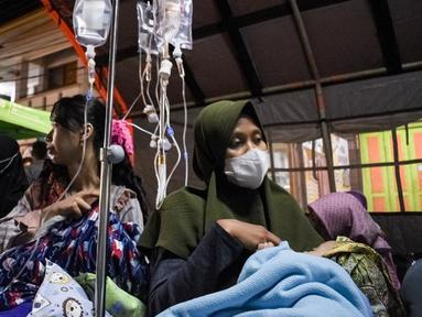 Pasien dievakuasi ke tenda darurat yang didirikan di luar RSUD Sumedang setelah atap dan dinding rusak akibat gempa magnitudo 4,8 di Sumedang, Jawa Barat, Senin (1/1/2024). (Timur MATAHARI/AFP)