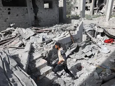 Seorang pria Palestina berjalan di antara reruntuhan bangunan di daerah yang menjadi sasaran serangan Israel di Khan Yunis di Jalur Gaza selatan, pada 2 April 2025. (Eyad BABA/AFP)