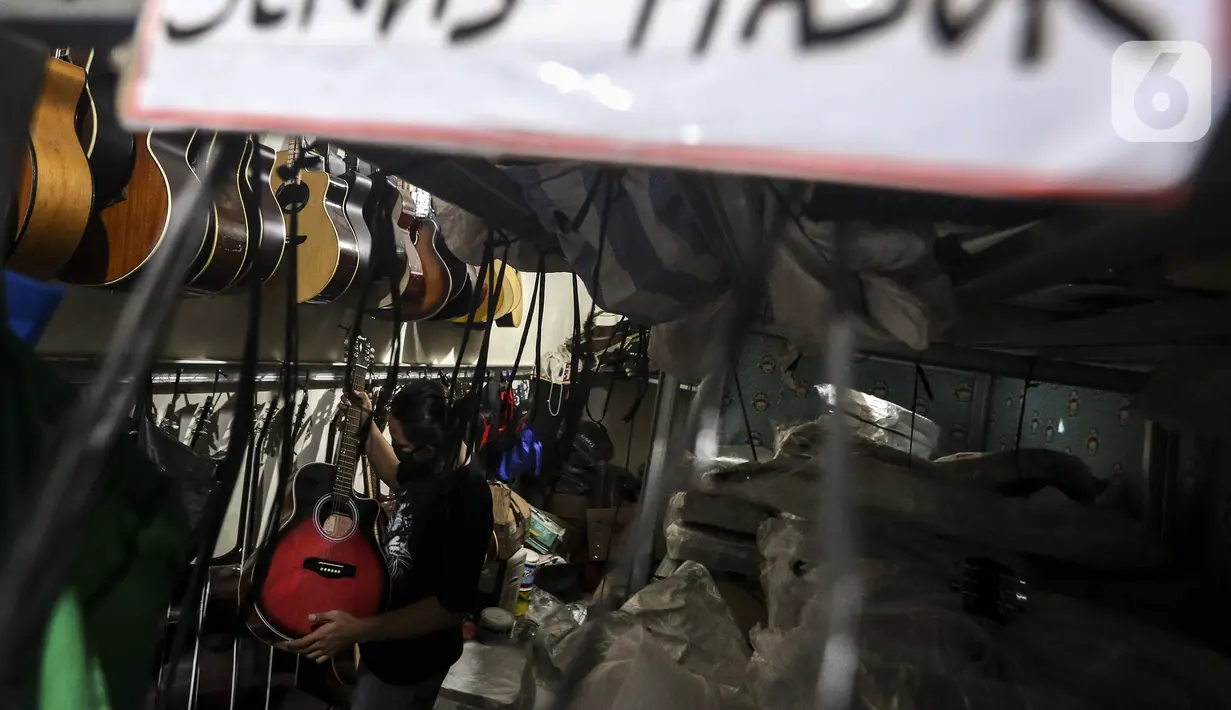 Harry memeriksa gitar klasik saat akan direparasi menjadi gitar listrik di toko kawasan Kedoya, Jakarta Barat, Selasa (9/2/2021). Selama pandemi COVID-19, servis gitar mengalami penurunan. (Liputan6.com/Johan Tallo)