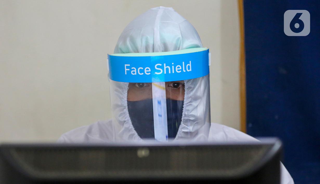 Petugas Dukcapil lengkap dengan APD melihat komputer di Kantor Kecamatan Pamulang, Tangerang Selatan, Senin (15/6/2020). Dukcapil Tangsel membuka layanan rekaman E-KTP menjelang Pilkada dengan menerapkan ketentuan New Normal guna mencegah penyebaran Virus Covid-19. (Liputan6.com/Fery Pradolo)