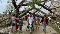 Warga berjalan melewati pohon tumbang setelah Topan Mocha mendarat di Kyauktaw di negara bagian Rakhine Myanmar, Senin (15/5/2023). (Photo by Sai Aung MAIN / AFP)