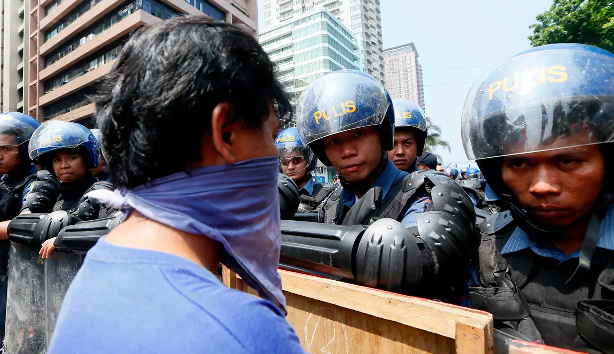 Polisi anti huru hara berjaga-jaga di depan Kedutaan Besar AS saat aksi protes berlangsung AS di Manila, Jumat (28/4). Demonstran mengecam imperealisme yang dilakukan oleh Amerika Serikat, Jepang dan China atas Asia Tenggara. (AP Photo / Bullit Marquez)