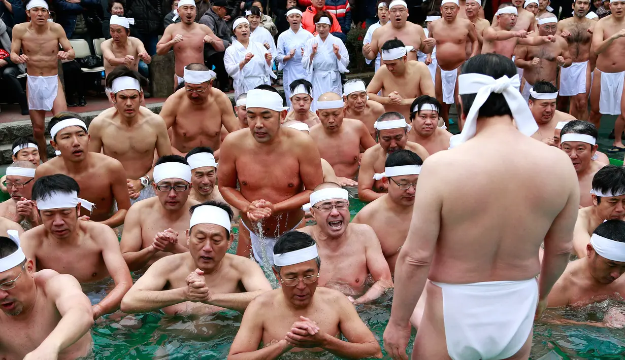 Ekpresi para peserta saat berendam di kolam air dingin di Teppozu Inari Shinto Shrine di Tokyo, Jepang (8/1). Acara tersebut merupakan ritual musim dingin yang diyakini dapat menjaga kesehatan mereka. (AP Photo/Shizuo Kambayashi)