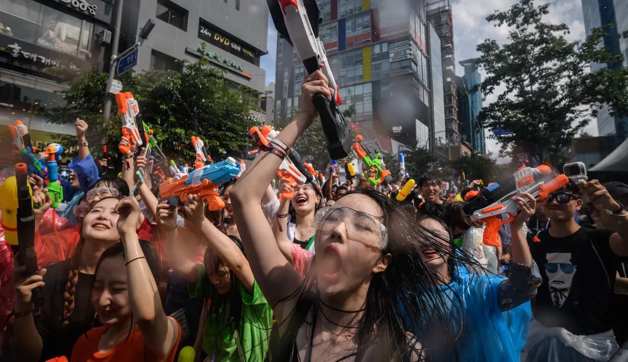 Para peserta bersuka ria selama Festival pistol air Sinchon di area Sinchon, Seoul, Minggu (7/7/2019). Festival musim panas yang membawa permainan air ke tengah kota ini cukup digandrungi baik warga lokal maupun wisatawan asing. (Photo by Ed JONES / AFP)