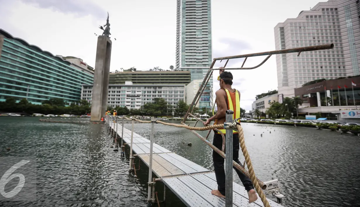 Pekerja membawa penyanggah di kolam Bundaran HI, Jakarta, Rabu (23/3). Pemasangan penyanggah bertujuan untuk menahan Tugu Selamat Datang dari getaran saat Bor Antareja proyek Mass Rapid Transit (MRT) melintas dibawahnya. (Liputan6.com/Faizal Fanani)