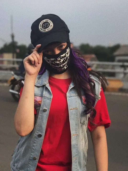 Adik Bryan Domani tampil kece dengan kaos berwarna merah. Penampilannya lebih hidup dengan perpaduan rompi denim. Gaya rambut bergelombang hair streak berwarna ungu ini membuat penampilannya semakin modis. (Liputan6.com/IG/@megandomani1410)