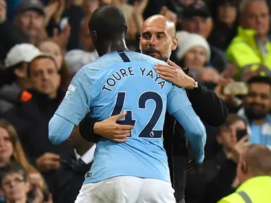 Pelatih Manchester City, Pep Guardiola, memeluk Yaya Toure usai laga melawan Brighton and Hove Albion di Stadion Etihad, Rabu (9/5/2018). Laga tersebut menjadi ajang perpisahan sang pemain bersama The Citizens. (AFP/Paul Ellis)