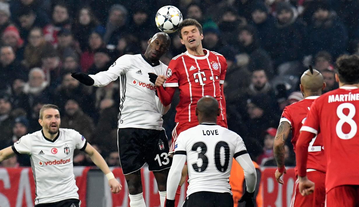 Gelandang Besiktas, Atiba Hutchinson berebut bola dengan pemain Bayern Munchen, Thomas Mueller pada pertandingan pertama babak 16 besar Liga Champions di Allianz Arena, Selasa (20/2).  Bayern melumat Besiktas lima gol tanpa balas. (Thomas KIENZLE/AFP)