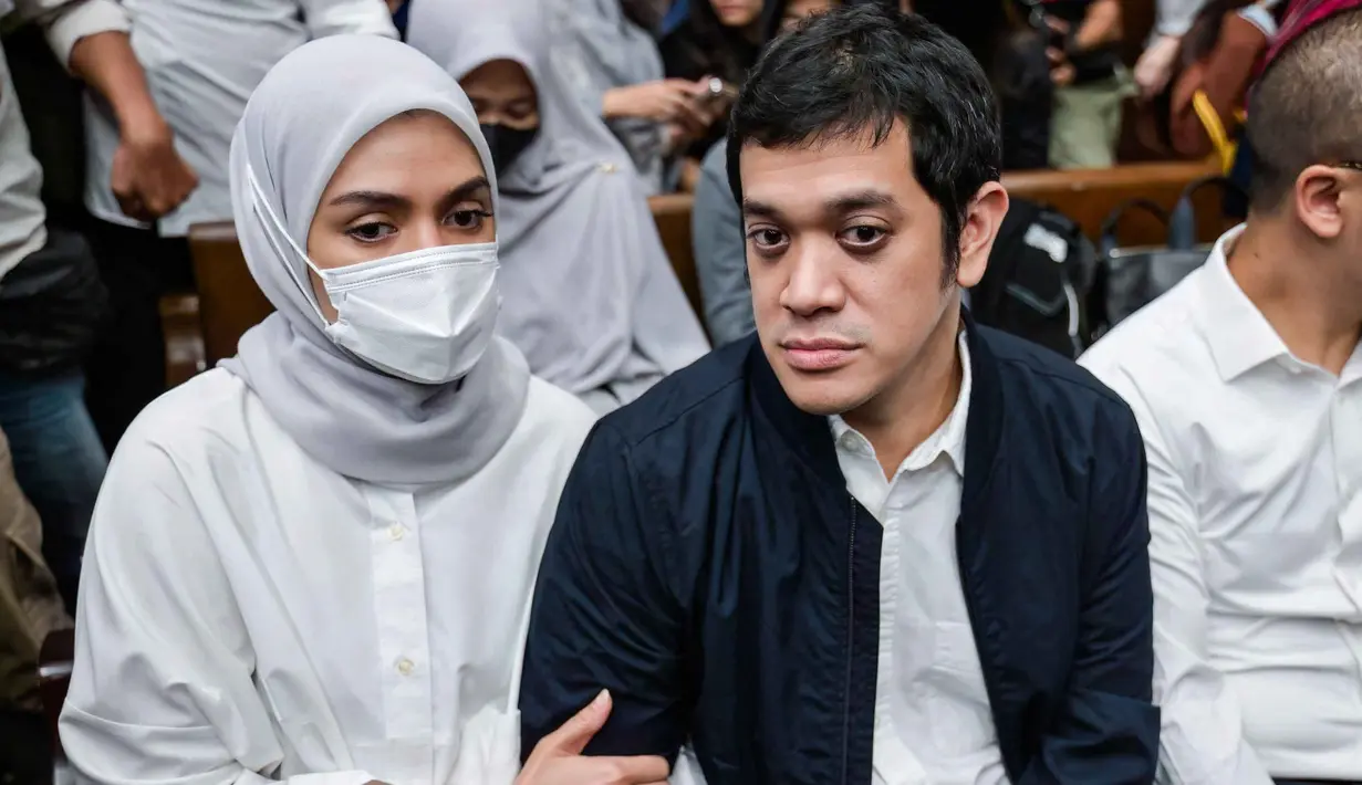 Sebelumnya, Muhammad Kerry Adrianto Riza didakwa melakukan pengaturan agar PT Jenggala Maritim Nusantara (JMN), perusahaan miliknya, memenangkan pengadaan sewa kapal dalam kerja sama dengan Pertamina. Tampak dalam foto, mantan Wakil Direktur Optimalisasi Produk di PT Kilang Pertamina Internasional, Muhammad Kerry Adrianto Riza (kanan), yang juga putra pengusaha Riza Chalid, didampingi istrinya Atya Sardadi (kiri), sesaat sebelum mengikuti sidang pembacaan vonis di Pengadilan Tindak Pidana Korupsi, Jakarta, Kamis 26 Februari 2026. (BAY ISMOYO/AFP)
