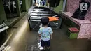 Seorang anak melihat sebuah perahu saat banjir di kawasan Kampung Melayu, Jakarta, Senin (8/11/2021). Warga belum mengungsi dan masih berharap air akan surut. (Liputan6.com/Faizal Fanani)