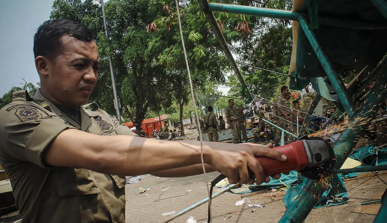 Seorang petugas saat membongkar kios-kios di lapangan IRTI Monas, Jakarta, Kamis (16/10/14). (Liputan6.com/Faizal Fanani)