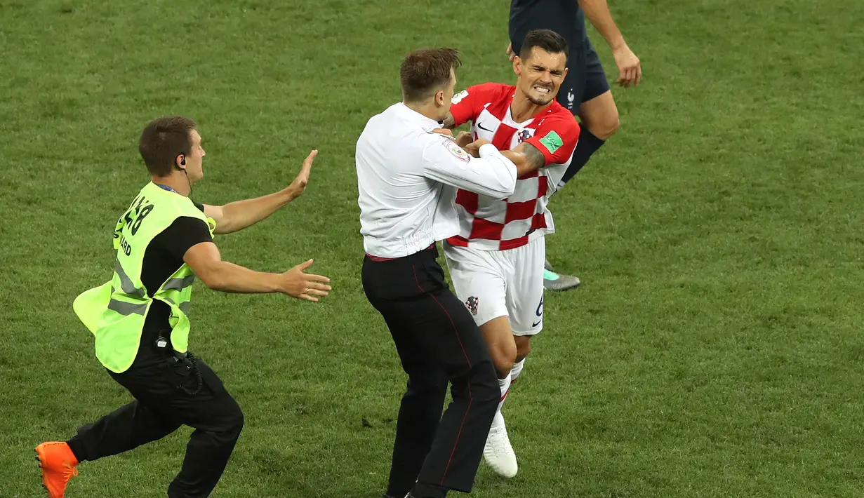Seorang penyusup mendekati bek timnas Kroasia, Dejan Lovren dalam laga final Piala Dunia 2018 melawan Prancis di Luzhniki Stadium, Minggu (15/7). Pertandingan sempat dihentikan sebelum para penyusup ditangkap oleh petugas. (AP/Thanassis Stavrakis)
