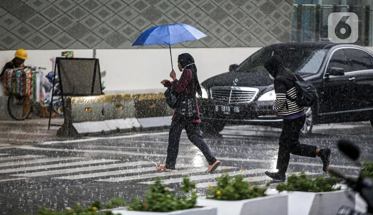Pejalan kaki yang menggunakan payung saat hujan deras menyeberang jalan di kawasan Thamrin, Jakarta, Rabu (23/11/2022). Kepala Pelaksana Badan Penanggulangan Bencana Daerah (BPBD) DKI Jakarta Isnawa Adji mengimbau masyarakat untuk mengurangi aktivitas di luar rumah apabila Jakarta mengalami cuaca ekstrem. (Liputan6.com/Faizal Fanani)
