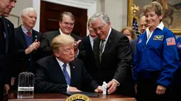Mantan astronot Apollo 17 Jack Schmitt memberikan mainan Astronot ke Presiden Donald Trump usai menandatangani kebijakan untuk mengirim astronot AS kembali ke bulan dan Mars di Ruang Roosevelt Gedung Putih, Washington (11/12). (AP Photo/Evan Vucci)