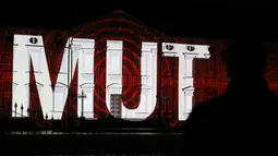 Seorang pengunjung menikmati pemandangan Istana Bellevue yang diterangi proyeksi cahaya bertuliskan "Mut", yang bermakna keberanian, di Berlin, ibu kota Jerman, 17 Desember 2020. Pertunjukan cahaya bertema "Lichtblick" (Seberkas Harapan) ini digelar di Istana Bellevue di Berlin. (Xinhua/Shan Yuqi)