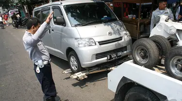 Sebuah mobil diderek petugas Dishub karena parkir sembarangan di jalan Pramuka, Jakarta, Kamis (18/9/2014) (Liputan6.com/Faizal Fanani)