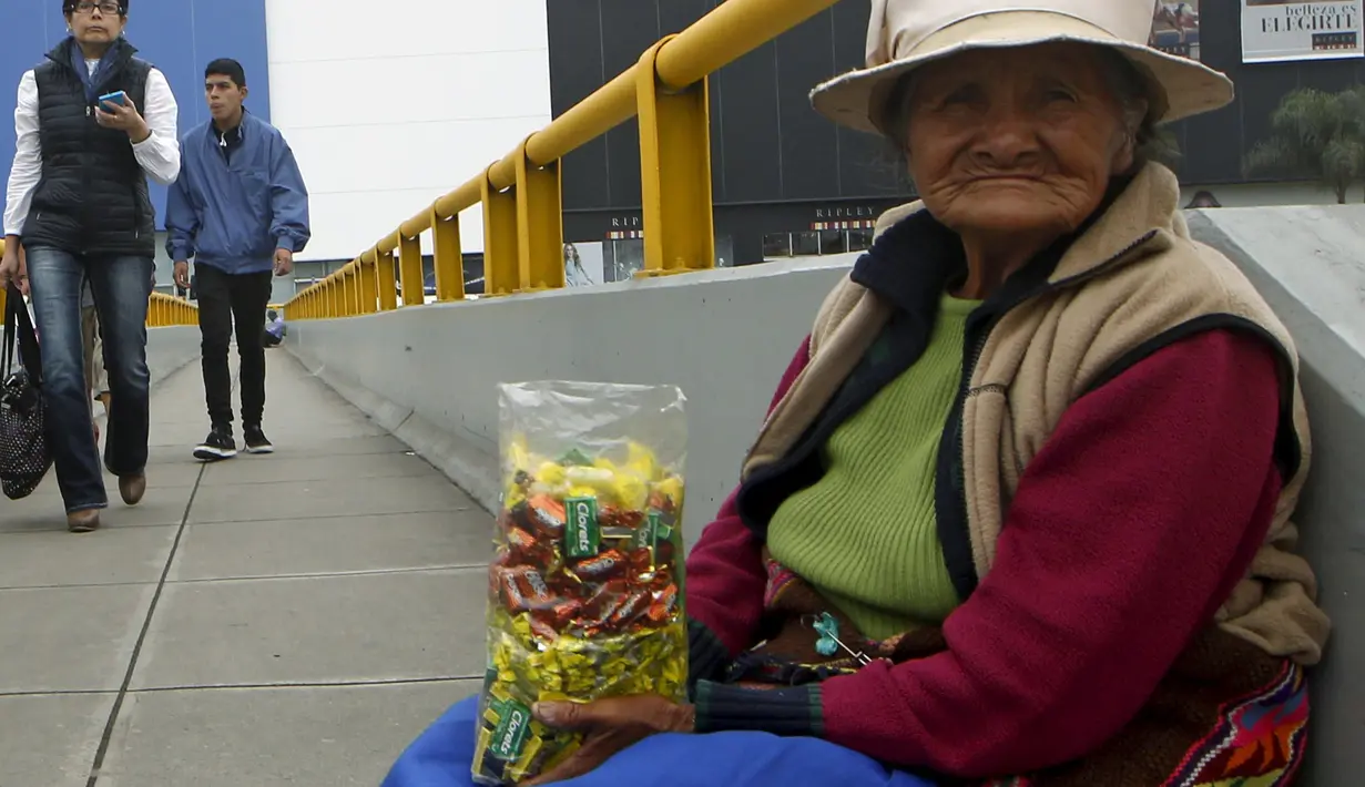 Alejandra Baldani (78) memegang permen jualannya sambil menunggu pembeli di jembatan penyeberangan di distrik San Borja, Lima, 22 Oktober 2015. Baldani mendapatkan sekitar USD 3 per hari dari hasil berjualan permen. (REUTERS / Mariana Bazo)