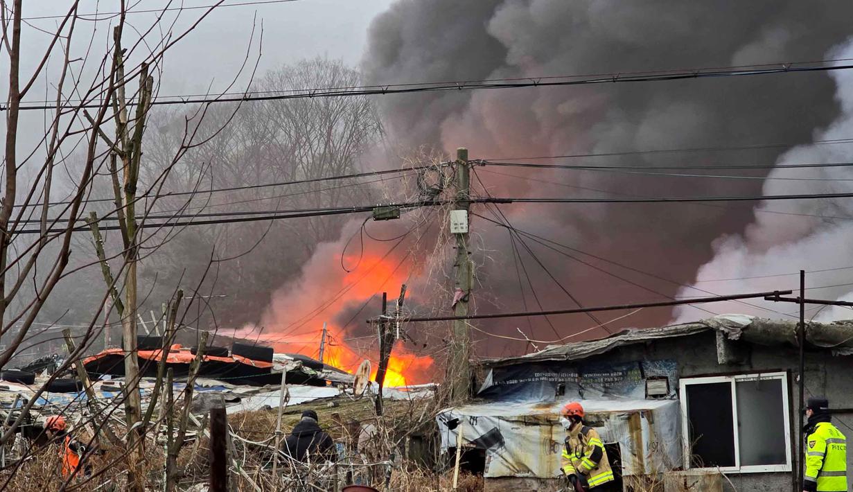 85 unit mobil pemadam diterjunkan ke lokasi kejadian. Tampak dalam foto, petugas pemadam kebakaran berjuang memadamkan api di permukiman kumuh Desa Guryong, pemukiman informal terbesar di Seoul, Korea Selatan, pada Jumat 16 Januari 2026. (YONHAP/AFP)