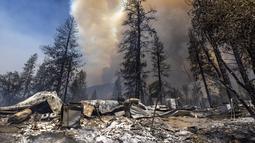 Properti yang hancur tertinggal di belakangnya saat api melahap hutan dekat Midpines, timur laut Mariposa, California (23/7/2022). Api yang bergerak cepat membakar di luar Taman Nasional Yosemite telah memaksa evakuasi, menghanguskan lebih dari 11.500 hektar dan telah menghancurkan beberapa rumah sejak mulai Jumat sore. (AFP/DAVID MCNEW)