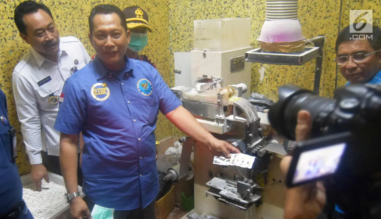 Kepala BNN Komjen Pol, Budi Waseso menunjukkan barang bukti pencetak pil saat pengungkapan kasus pabrik pil PCC di Semarang, Jawa Tengah, Senin (4/12). Sejumlah barang bukti dan 11 karyawan yang bekerja di rumah tersebut ditahan BNN. (Liputan6.com/Gholib)