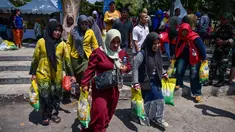 Warga membawa beras usai mengantre membeli kebutuhan pokok di salah satu pasar di Surabaya, Jawa Timur pada Selasa 23 September 2025. (Juni KRISWANTO/AFP)