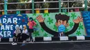 Warga berpose dengan mural yang mengajak orang untuk memakai masker di tengah pandemi Covid-19 di Surabaya, Jawa Timur, Minggu (25/10/2020). Mural di sepanjang dinding itu sebagai sarana imbauan kepada masyarakat untuk menerapkan protokol kesehatan pencegahan penularan COVID-19. (Juni Kriswanto/AFP)