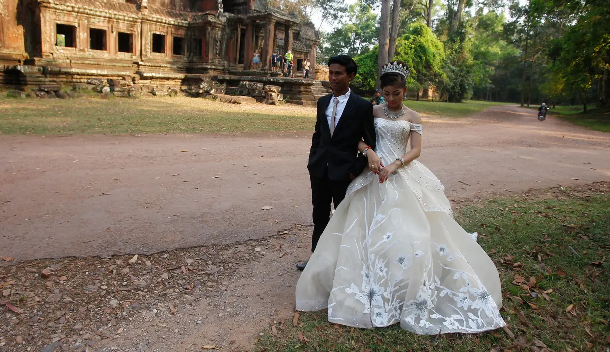 Sepasang pengantin baru melakukan foto pernikahan mereka di kompleks kuil Angkor Wat, sebuah candi ikonik dan bersejarah di Kamboja, 14 Maret 2018. Candi ini dibangun pada pertengahan abad ke-12 dan memakan waktu selama 30 tahun. (AP Photo/Heng Sinith)