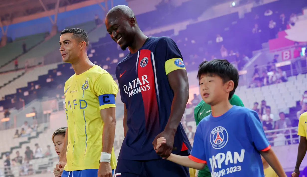 Pemain Al Nassr, Cristiano Ronaldo (kiri), dan pemain PSG, Danilo Pereira (tengah), berjalan menuju ke lapangan sebelum pertandingan uji coba antara Al Nassr melawan PSG yang berlangsung di Nagai Stadium, Osaka, Selasa (25/7/2023). (AFP/Paul Miller)